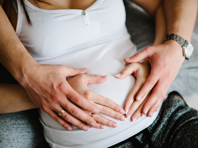 Ausgeschnittenes Bild eines Mannes, der den Bauch seiner schwangeren Frau hÃ¤lt.