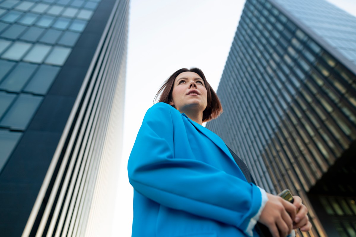 Geschäftsfrau im blauen Blazer steht in der Nähe eines Bürogebäudes