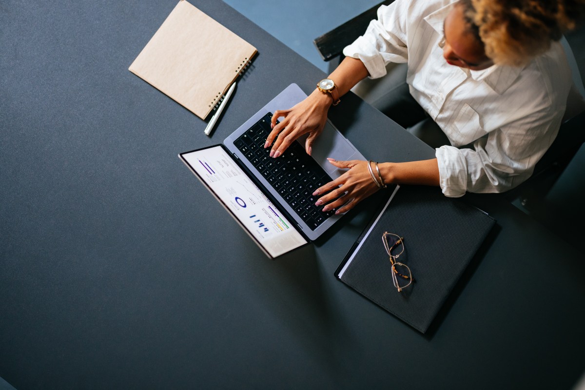 Eine Frau sitzt am Laptop und arbeitet.