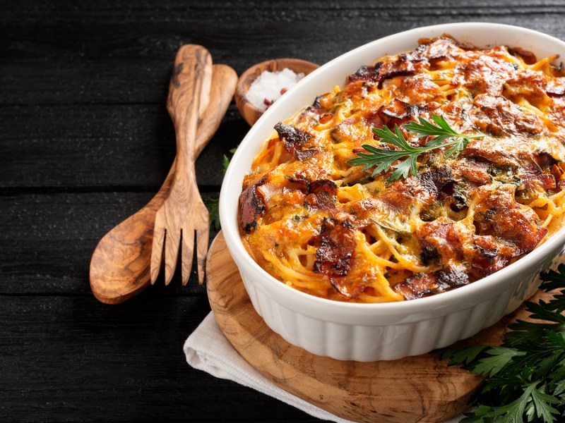 Auflaufform mit Spaghetti-Lasagne auf schwarzem Hintergrund.