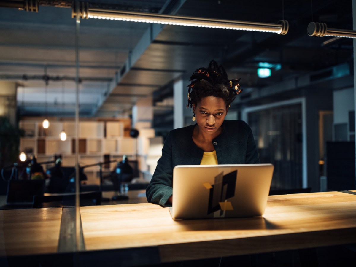 GeschÃ¤ftsfrau arbeitet spÃ¤t am Laptop, wÃ¤hrend sie im BÃ¼ro am Schreibtisch sitzt