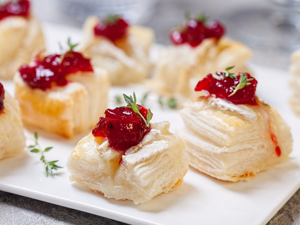 BlÃ¤tterteig-HÃ¤ppchen mit Camembert auf einem Tablett.