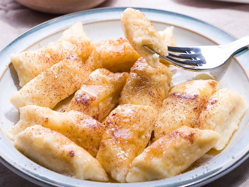 Bratapfel-Gnocchi mit Zimt und Zucker in einem tiefen Teller. Eine Gnocchi ist aufgespieÃŸt auf einer Gabel.