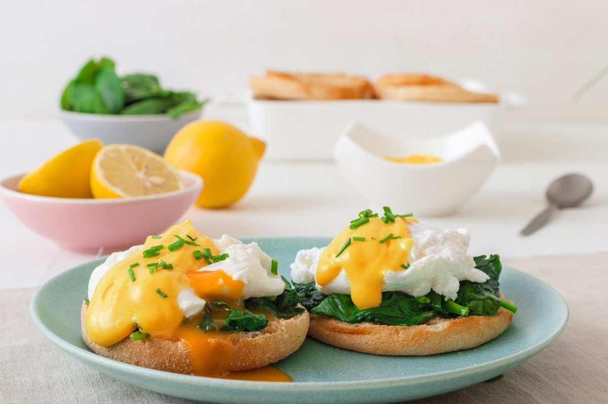 Eggs Florentine aus Spinat mit KÃ¤sesoÃŸe auf einem blauen Teller.