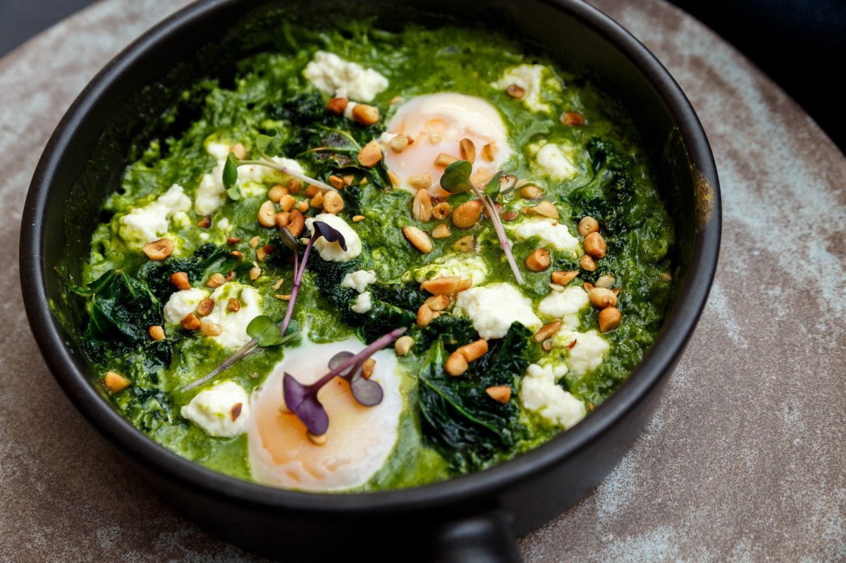 Pfanne mit grÃ¼nem Shakshuka, Pinienkernen und pochierten Eiern