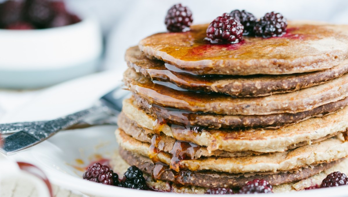 Ein Stapel Haferflocken-Pancakes mit frischen Brombeeren und Sirup.