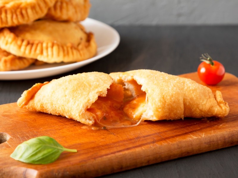 Ein Panzerotti mit Tomate-Mozzarella-FÃ¼llung, der in der Mitte durchgeschnitten wurde.