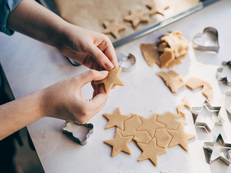 Junge Frau bereitet Weihnachtsplätzchen auf dem Tisch zu.