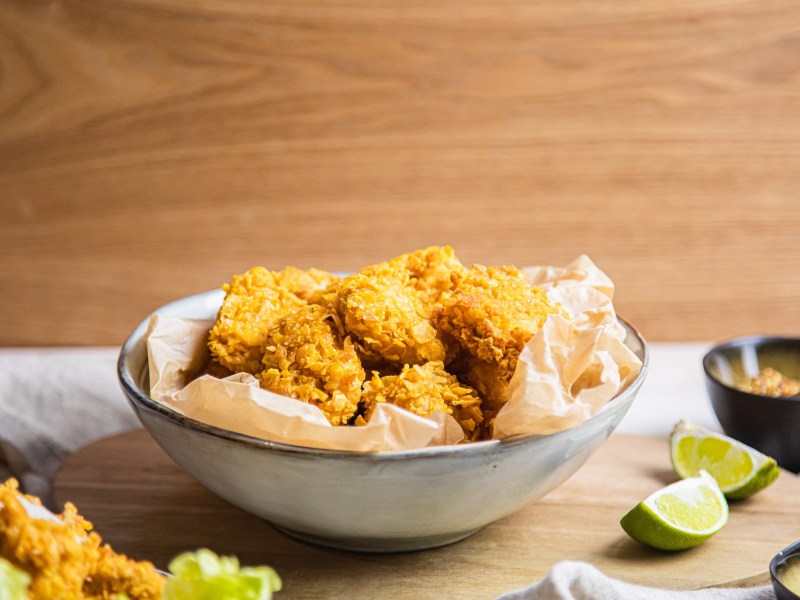 Eine Schale vegane Chicken Nuggets, daneben Limettenspalten.