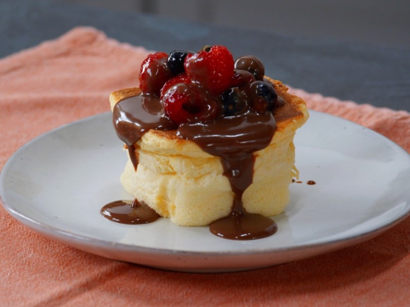 Ein fluffiger WÃ¼rfelkuchen mit SchokosoÃŸe und frischen Beeren auf einem Teller.