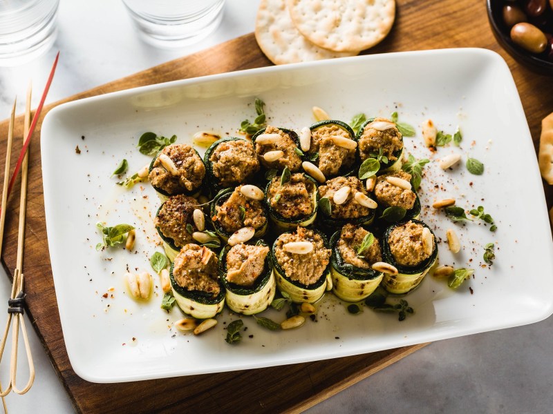 Zucchini-RÃ¶llchen mit Olivencreme auf einem Tablett.