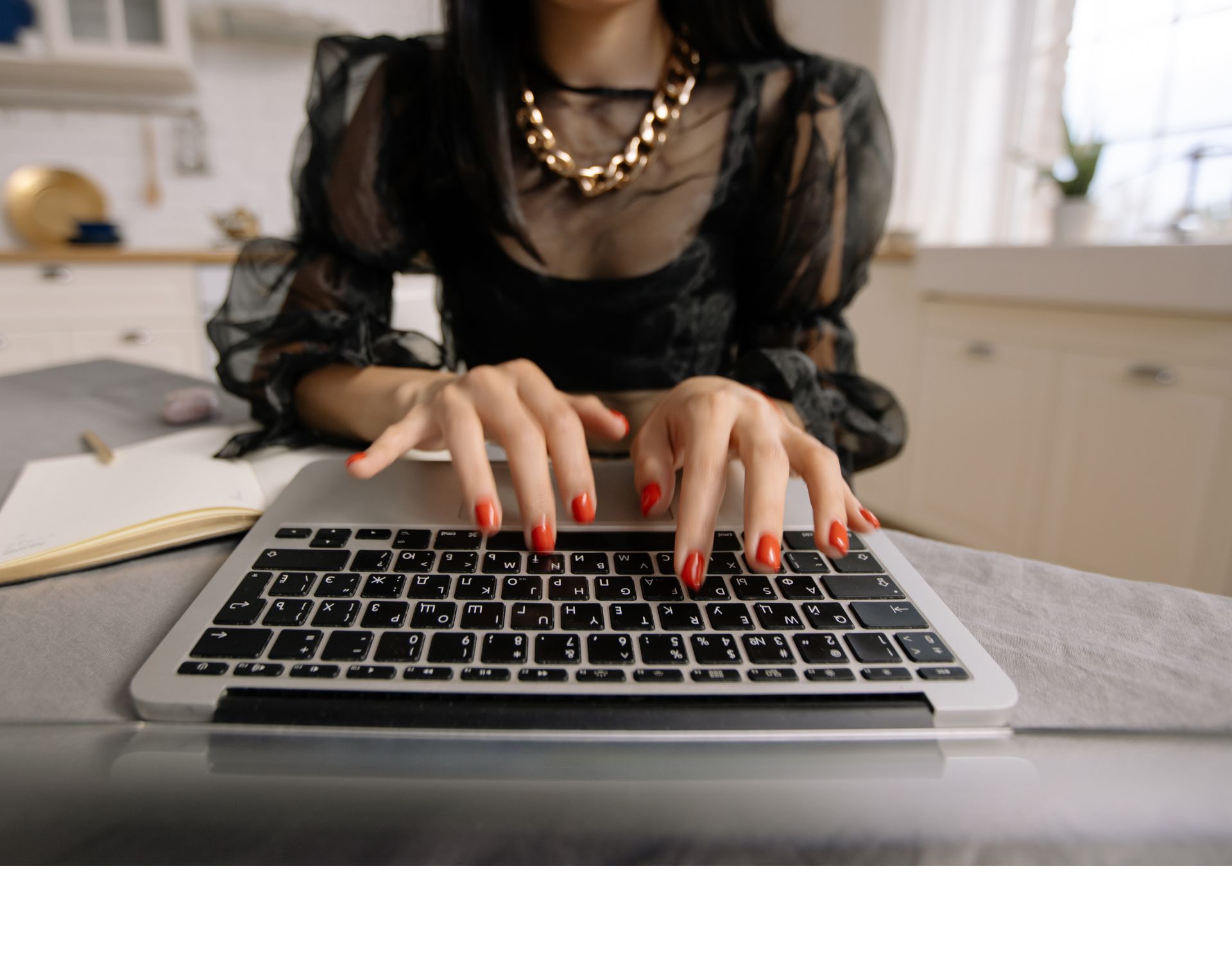 Eine Frau mit roten Fingernägeln tippt auf einer Tastatur.