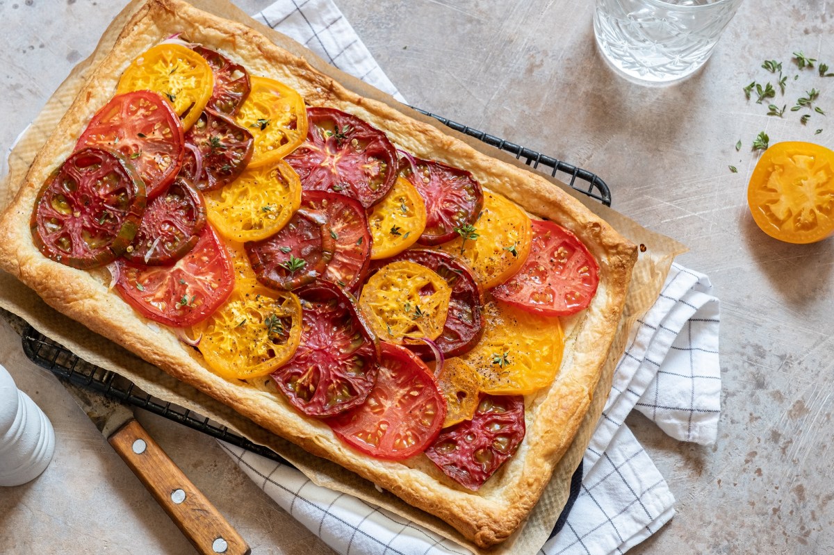 BlÃ¤tterteig-Tarte mit Tomaten auf einem Kuchengitter, das auf einem Geschirrtuch liegt.