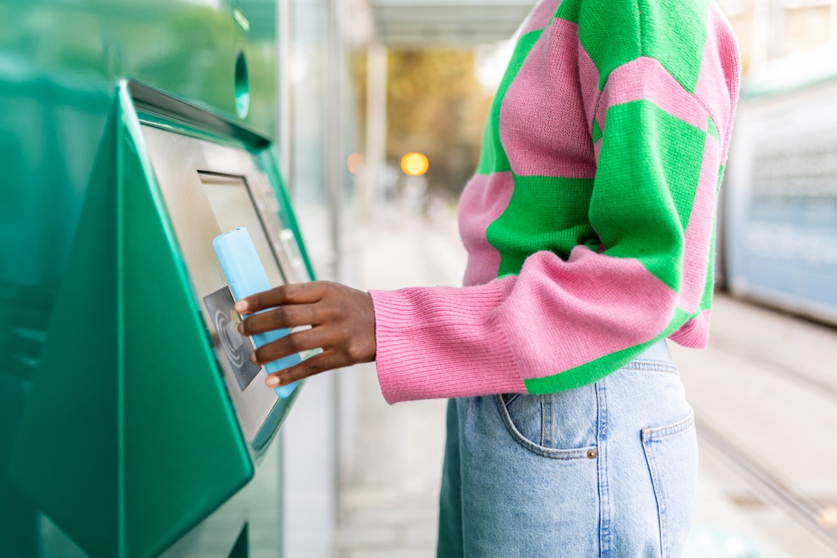 Frau in pink, grÃ¼nen Pullover hebt Geld ab.