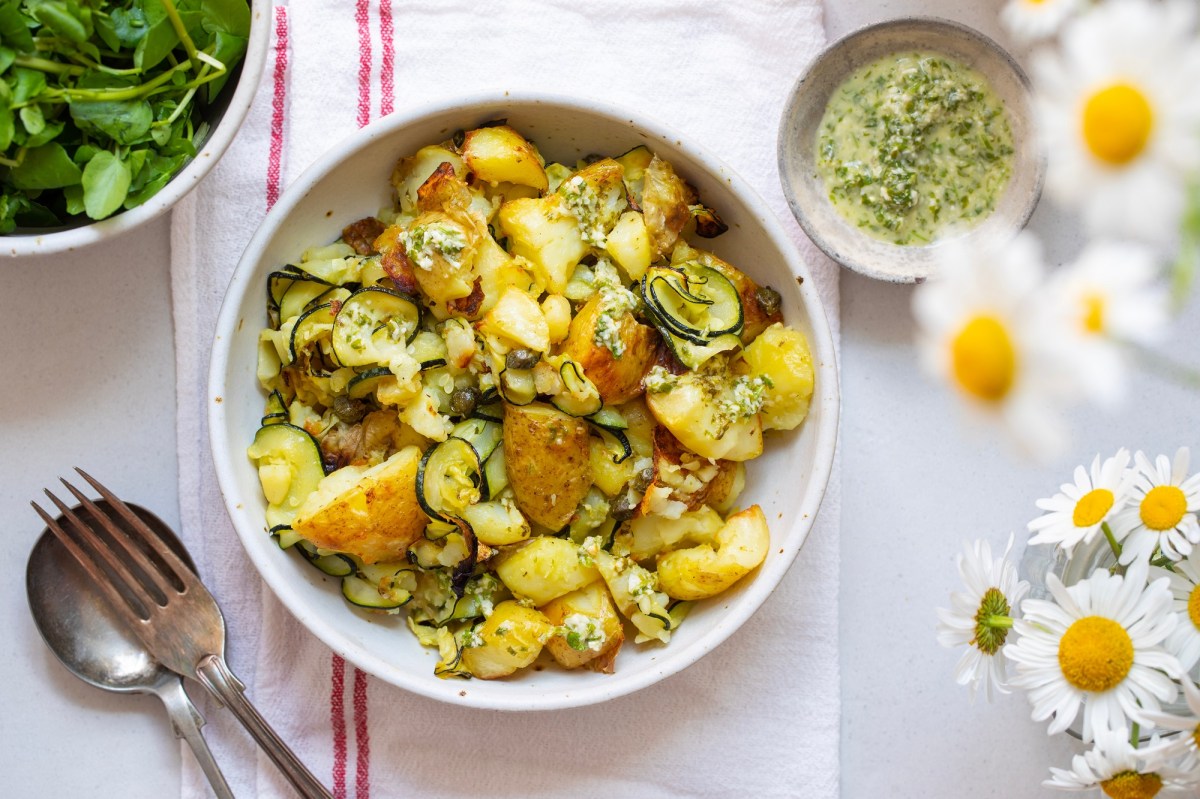 Kartoffelsalat mit gegrillter Zucchini in einer weiÃŸen Schale. Daneben steht eine Schale mit Dressing.