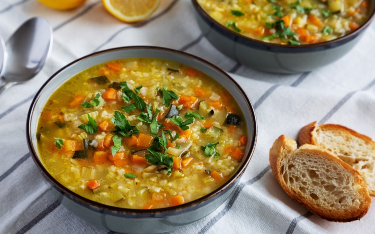 Eine SchÃ¼ssel Reissuppe. Daneben liegen 2 StÃ¼cke Brot.