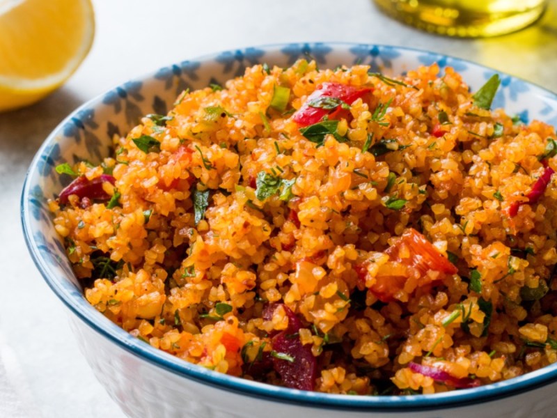 Eine SchÃ¼ssel mit tÃ¼rkischem Bulgursalat. Daneben liegt eine Zitronenspalte.