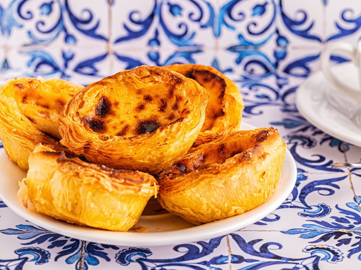 Ein Teller vegane PastÃ©is de Nata auf typischen blauen portugiesischen Fliesen.