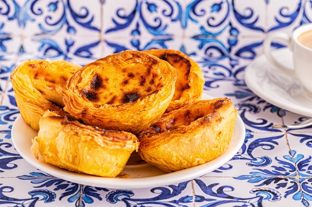 Ein Teller vegane PastÃ©is de Nata auf typischen blauen portugiesischen Fliesen.