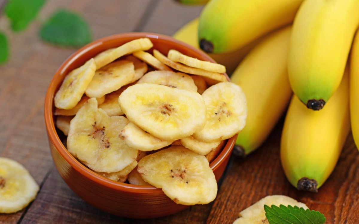 Bananenchips in einer SchÃ¼ssel. Daneben frische Bananen.