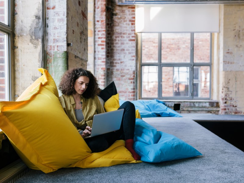 Frau arbeitet in der Chill-out-Zone im Büro an ihrem Laptop.