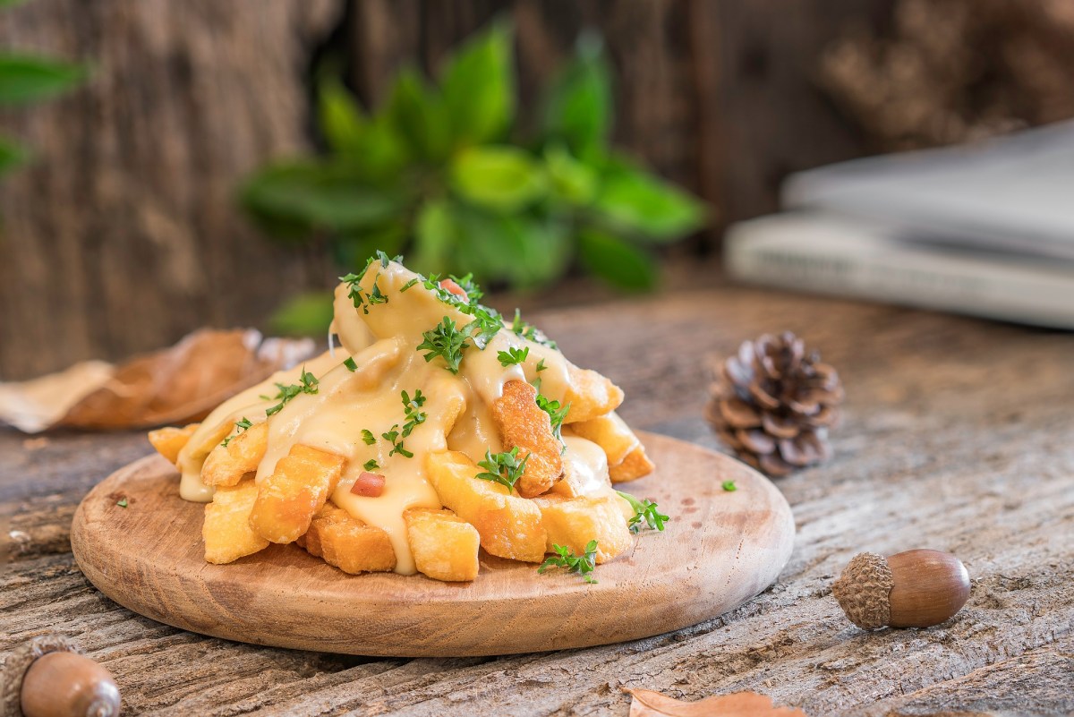 KÃ¤se-Pommes auf einem Brett, mit Petersilie bestreut.