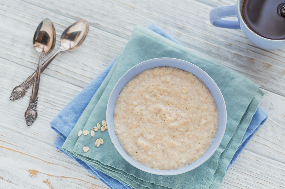 Schottischer Porridge in einer hellblauen SchÃ¼ssel, daneben ligeen zwei LÃ¶ffel.