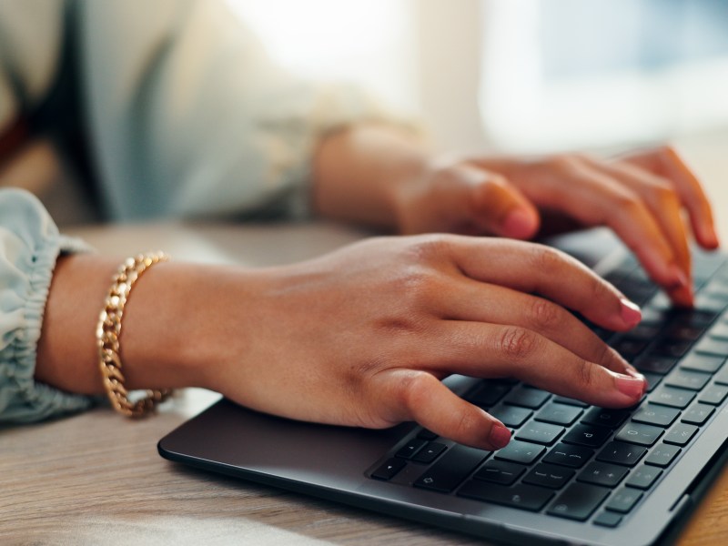 Eine Frau mit roten Fingernägeln tippt auf einer Tastatur.