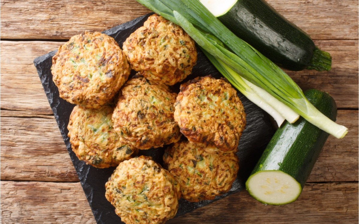 Mehrere Zucchini-BÃ¤llchen in der Draufsicht. Daneben liegen Zucchini und FrÃ¼hlingszwiebeln.