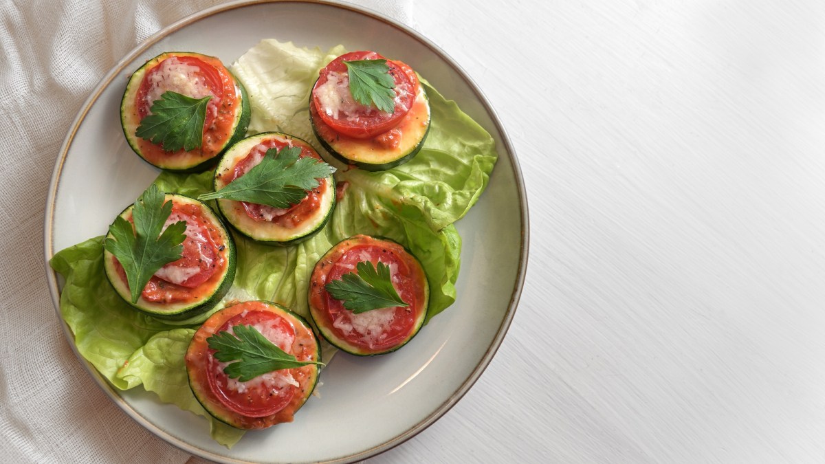 Zucchini-Bruschetta-HÃ¤ppchen mit Parmesan und Tomate auf einem Teller, Draufsicht.