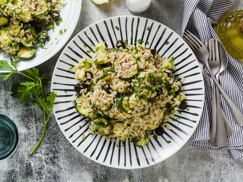 Zucchini-Reissalat auf einem blau-weiÃŸ gestreiften Teller.