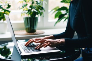 Frau tippt auf dem Laptop.