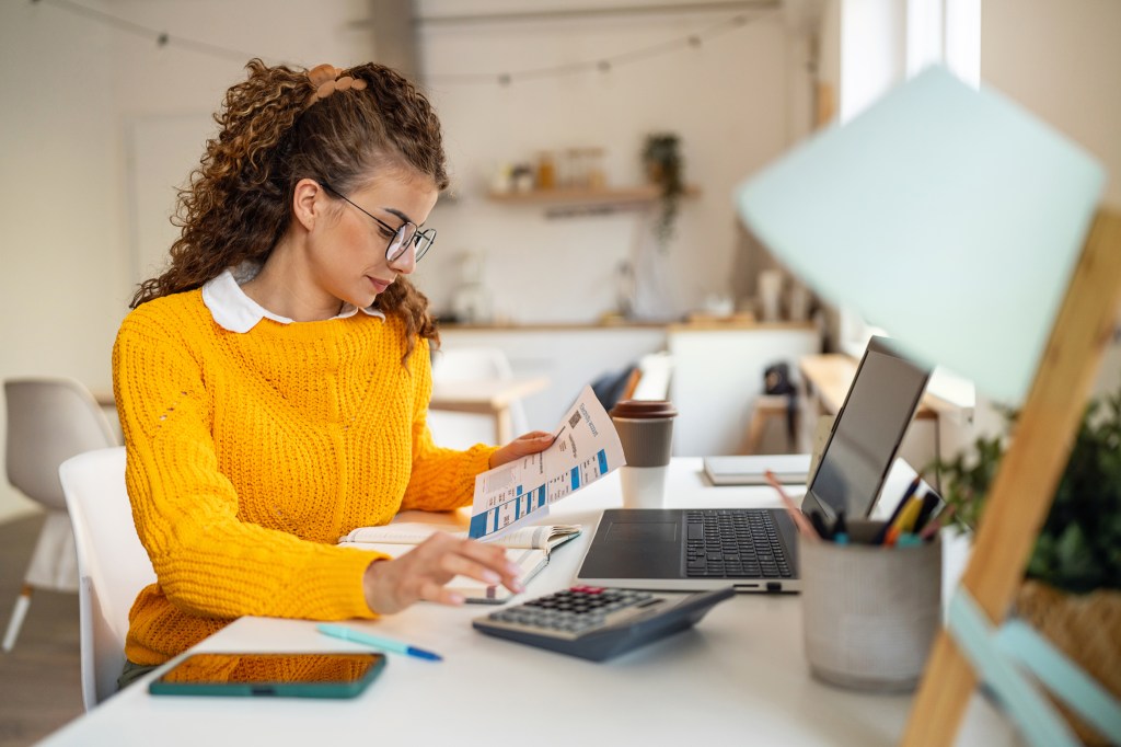 Steuererklärung: Junge Frau mit Taschenrechner, während sie ihre Finanzen organisiert.