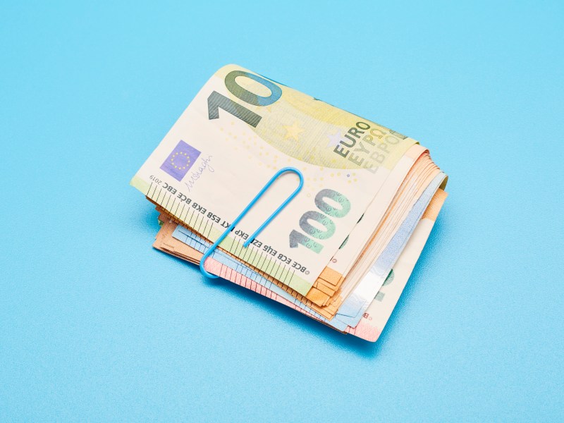 Stillleben mit einem Bündel Euro-Banknoten auf blauem Hintergrund.