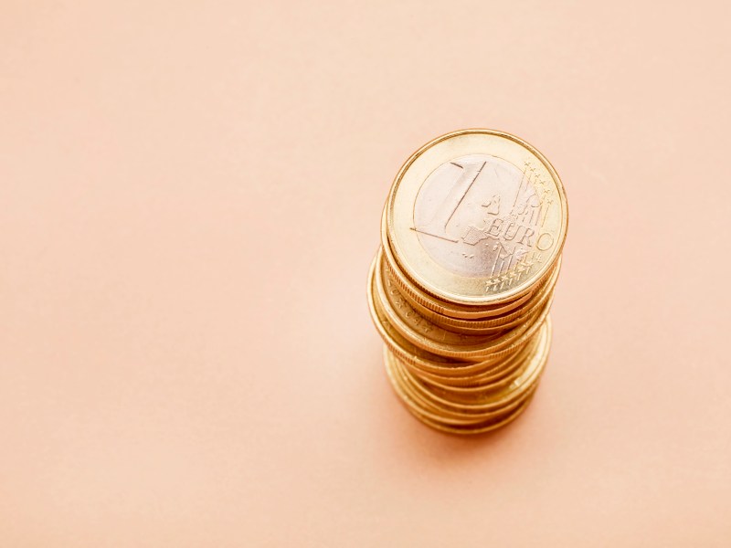Stapel von Ein-Euro-Münzen auf beigen Hintergrund.