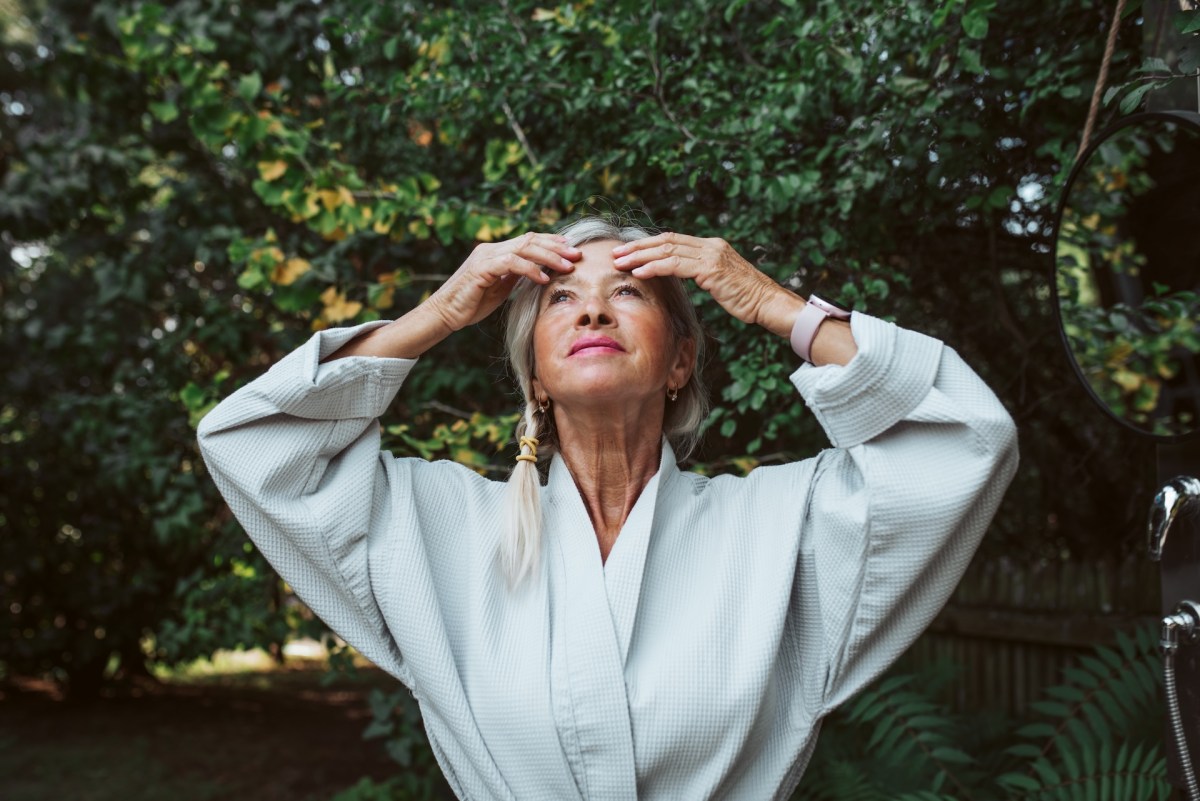 Ältere Dame streicht sich durchs Gesicht.