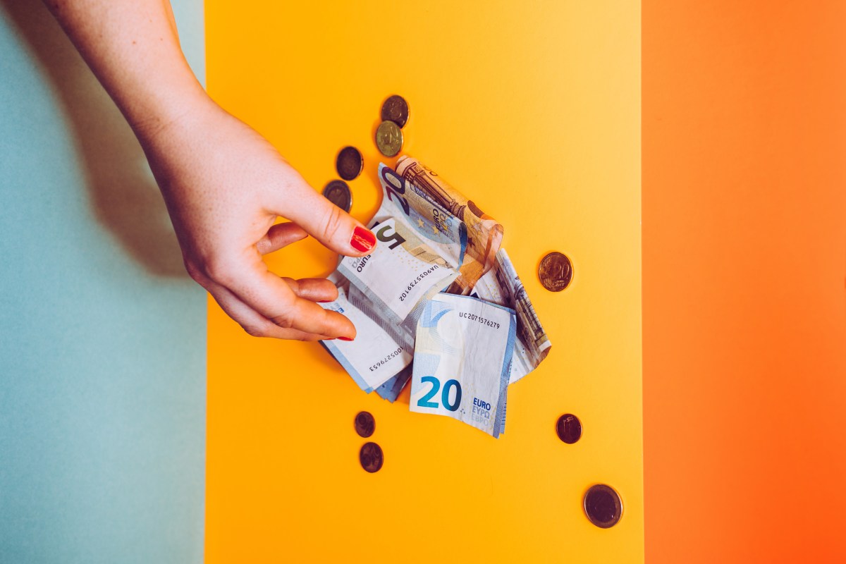 Eine Hand greift nach einem Geldschein.