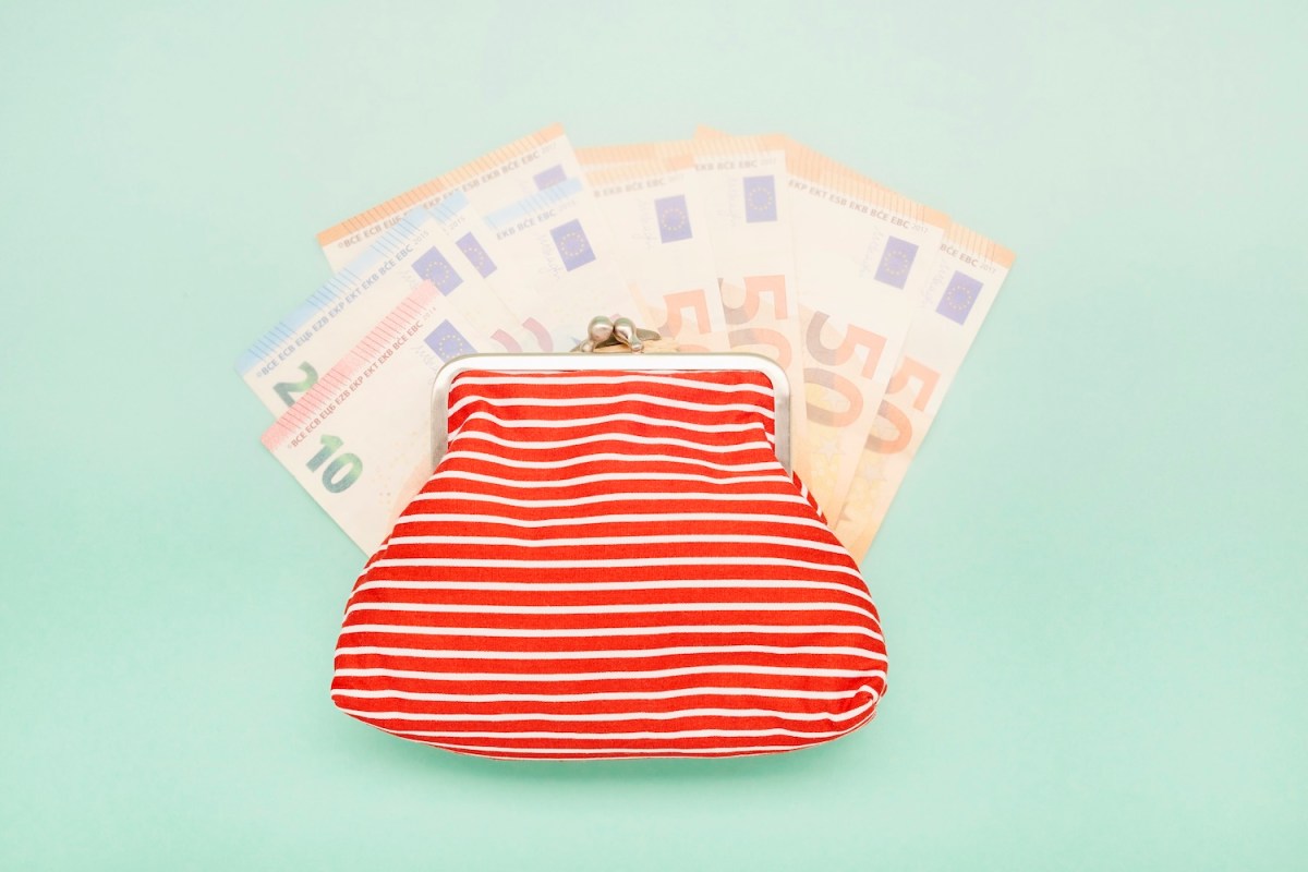 eine Aufnahme einer Brieftasche und Euro-Banknoten auf türkisfarbenem Hintergrund.