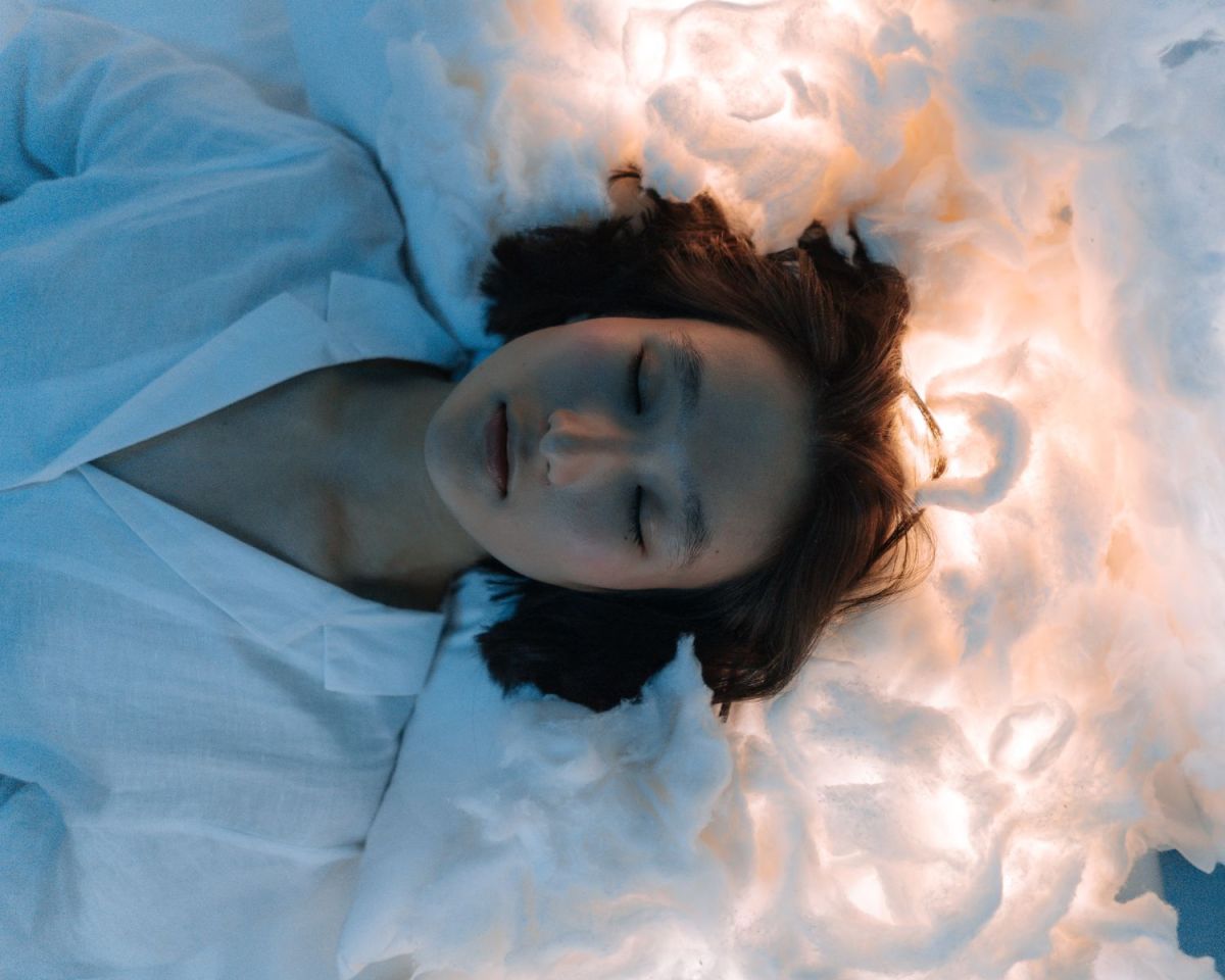 Frau schläft auf von unten angeleuchteten Wolken