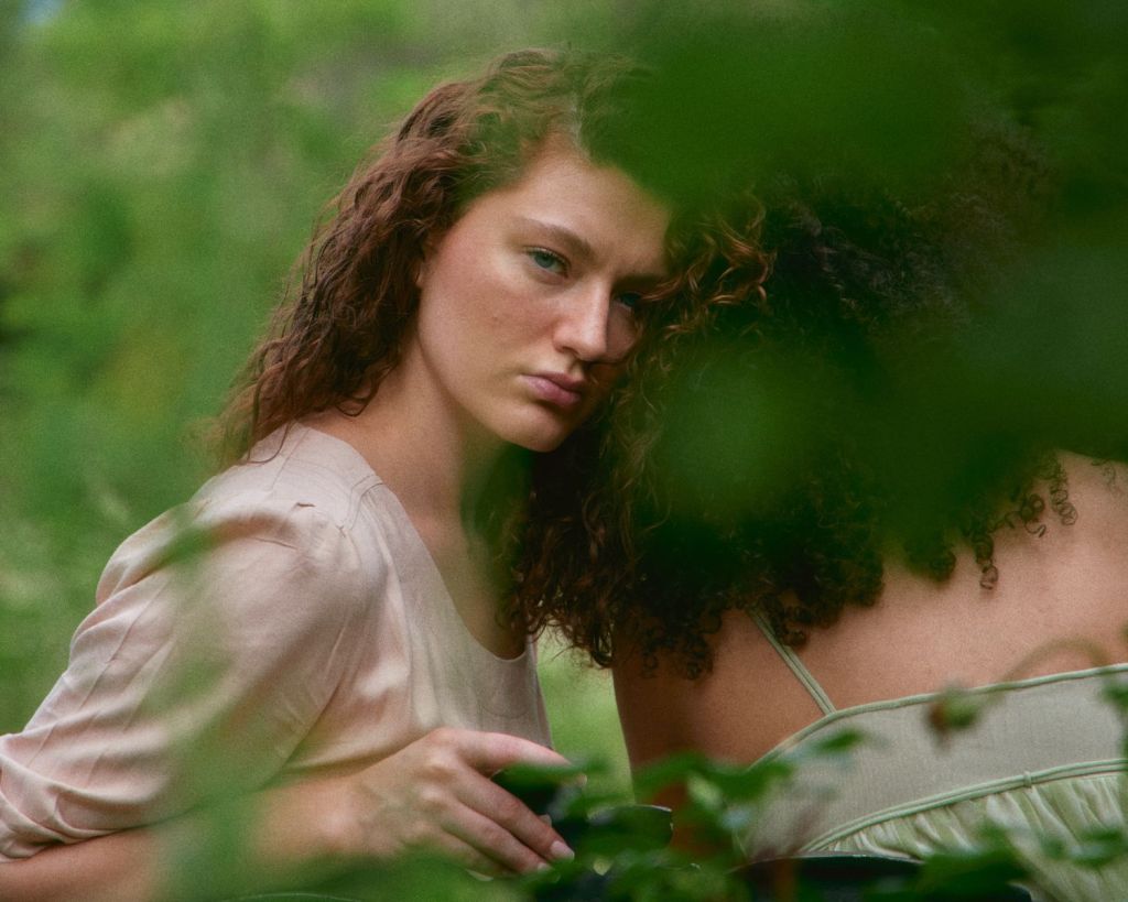 Frau lehnt sich an eine andere Frau und schaut in die Kamera.