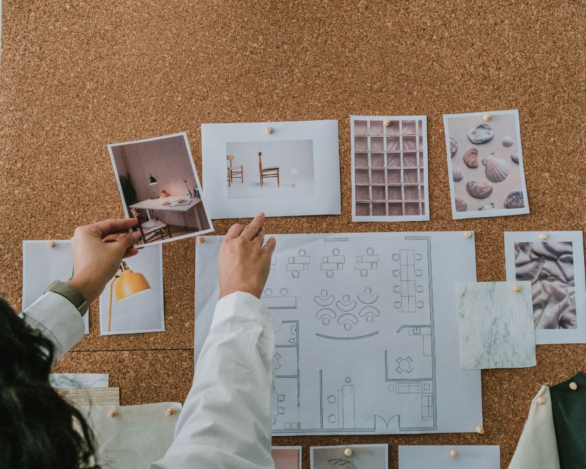Frau steckt Interior-Bilder an ein Kork-Board.