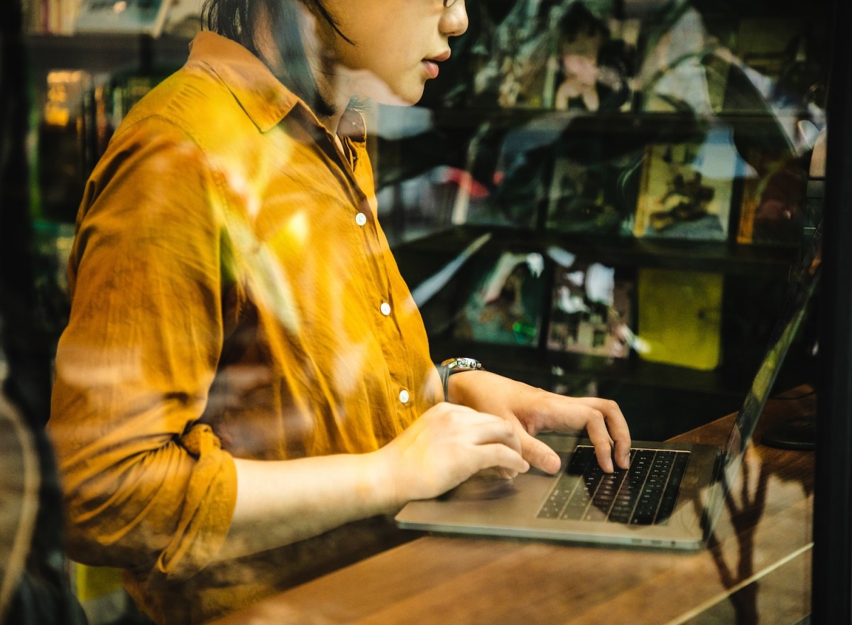 Asiatische Frau arbeitet remote an einem Laptop.