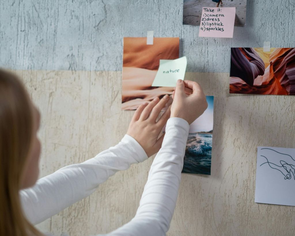 Frau pinnt Bilder an die Wand.