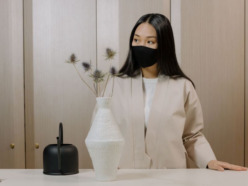 Frau mit Maske in einem beigefarbenen Wohnzimmer