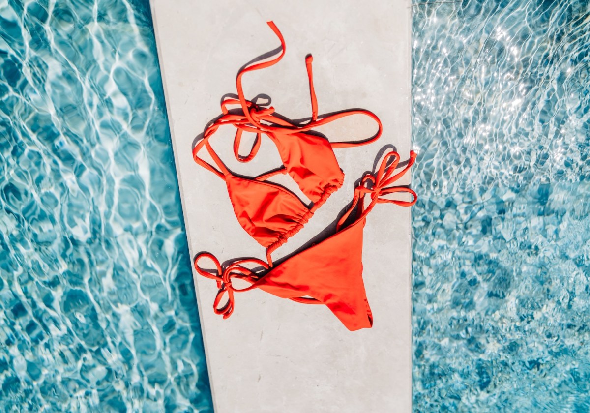 Ein roter Bikini liegt am Pool.