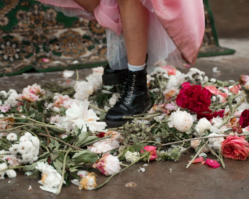 Frau mit Stiefeln steht auf Blumen