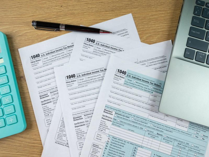 Steuerformulare, Taschenrechner und ein Laptop.