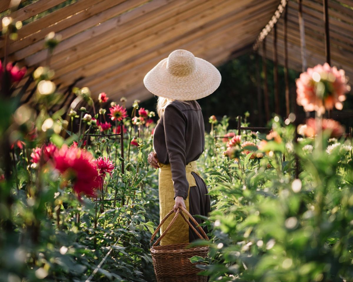 Frau steht mit dem Rücken zur Kamera in einem Garten mit Blumen
