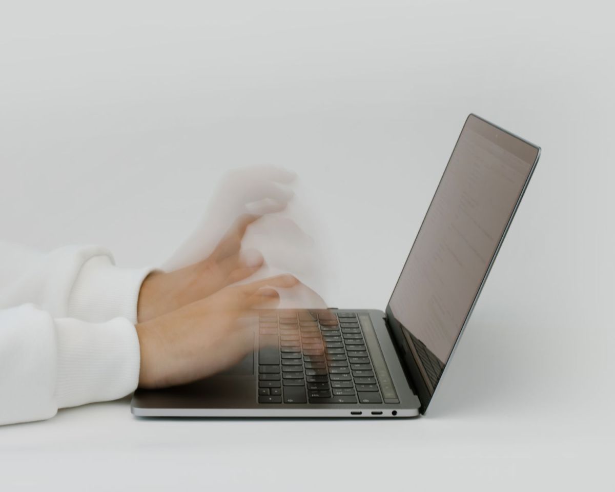 Verschwommene Hände tippen auf einem Laptop.