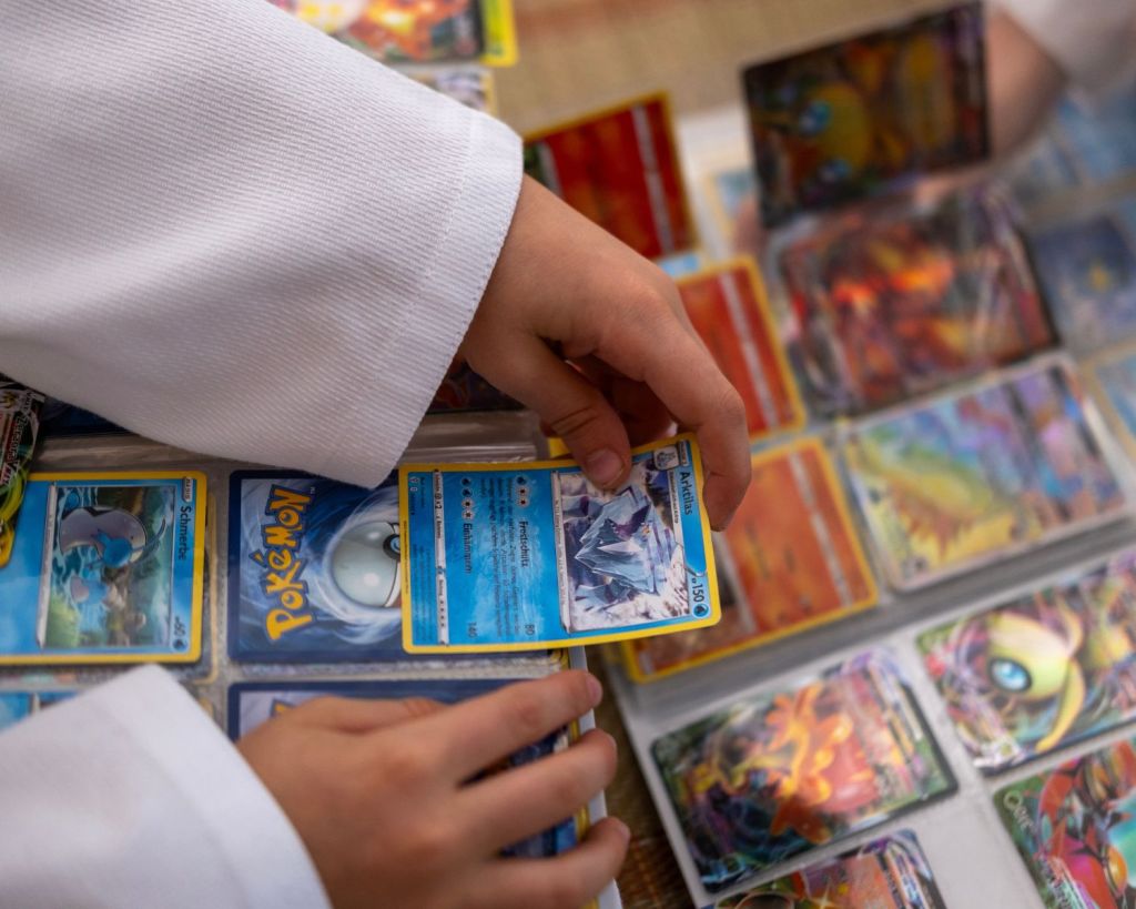 Kind zieht Pokémon-Karten aus einem Ordner